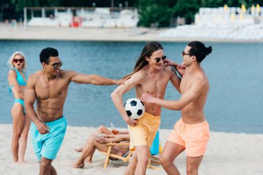 plajda futbol topu ile eğlenmek neşeli, genç çok kültürlü arkadaşlar