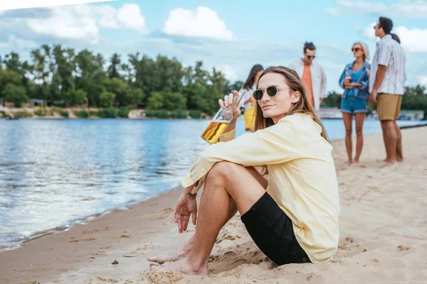 Jovem Bonito Sunglases Sentado Praia Perto Amigos Multiculturais — Fotografia de Stock