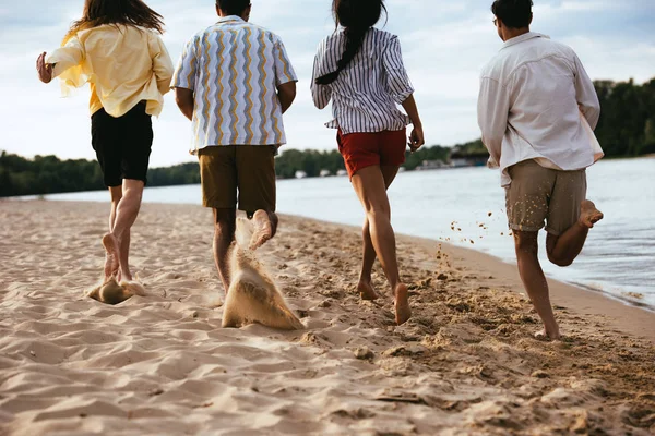 在河边的沙滩上奔跑的多民族朋友的背景 — 图库照片