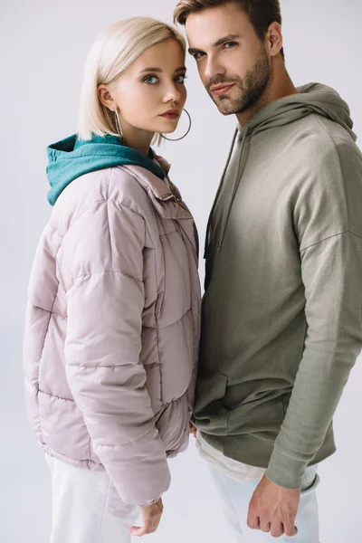 stylish blonde girl and bearded man in autumn outfits looking at camera isolated on grey