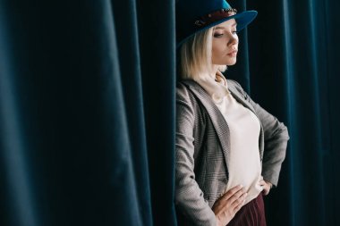 perde yakınında kalça elleri ile ayakta şapka ve ceket şık sarışın kız