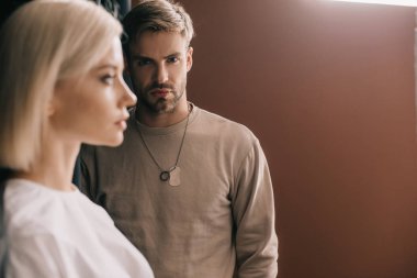 selective focus of attractive blonde girl and bearded young man on brown clipart