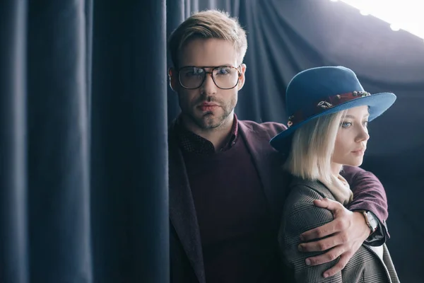 Jovem Elegante Óculos Abraçando Menina Loira Chapéu Perto Cortina — Fotografia de Stock