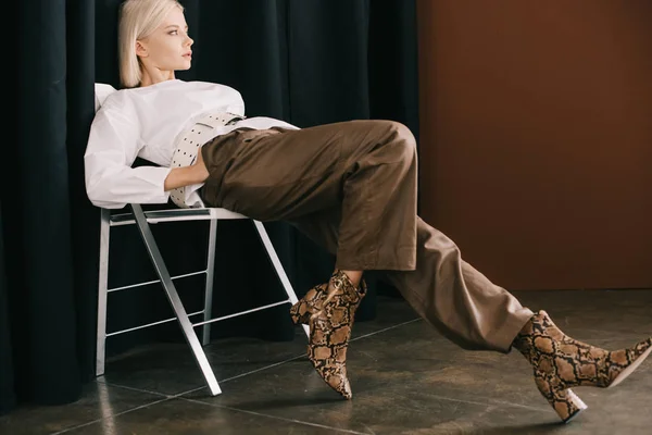 Stylish Blonde Woman White Blouse Boots Snakeskin Print Sitting Chair — Stock Photo, Image