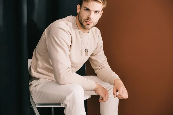 Man Casual Outfit Sitting Chair Looking Camera Curtain Brown — Stock Photo, Image