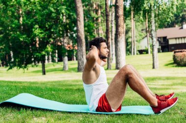 side view of bearded sportsman doing do abs on fitness mat  clipart