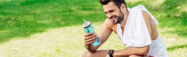 panoramic shot of happy bearded man looking at sport bottle  clipart