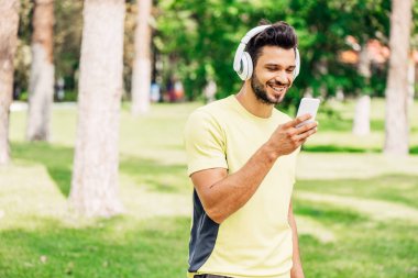 mutlu sakallı adam akıllı telefon bakarak ve müzik dinleme 