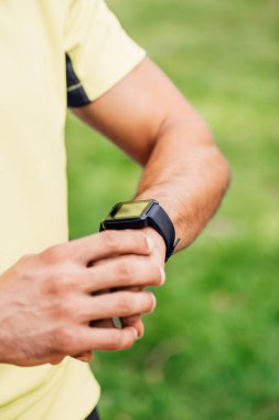 cropped view of sportsman touching fitness tracker outside  clipart