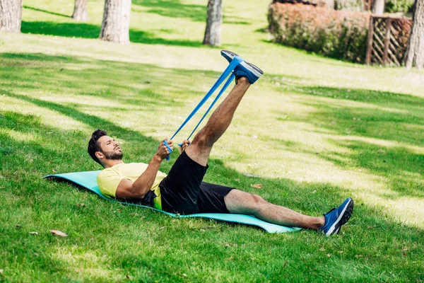 留胡子的男子锻炼与悬挂带 而躺在健身垫 — 图库照片