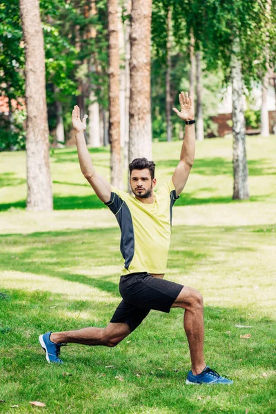 handsome bearded sportsman exercising on green lawn