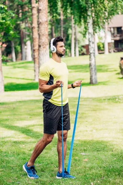 Schöner Mann Der Park Musik Hört Und Mit Spanngurten Trainiert — Stockfoto