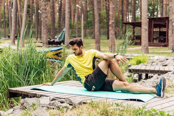 Hombre Barbudo Ropa Deportiva Calentándose Alfombra Fitness Cerca Piedras Árboles —  Fotos de Stock