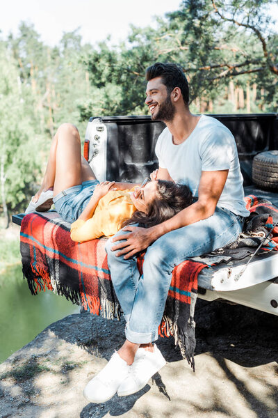 handsome bearded man smiling while girl lying on plaid blanket 