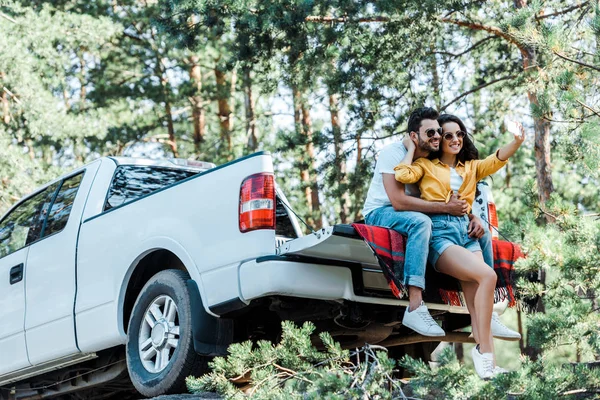 車や木の近くで男性と自分撮りを話す陽気な女性 — ストック写真