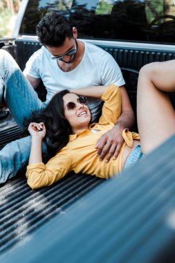 güneş gözlüğü yakışıklı adam seçici odak araba bagajında oturan ve kız bakarak 