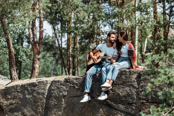 Brodaty Mężczyzna Gra Gitarze Akustycznej Pobliżu Kobiety Lesie — Zdjęcie stockowe