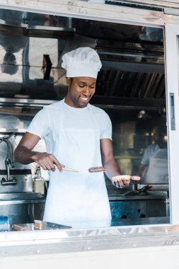 burger hazırlarken spatula tutan neşeli afrian amerikan adam 