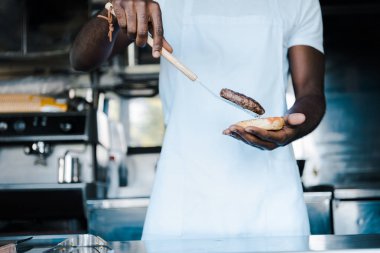 burger hazırlarken spatula tutan afrian amerikan adam kırpılmış görünümü 