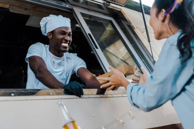 müşteriye karton plaka veren neşeli afrikalı-amerikalı adam düşük açı görünümü 