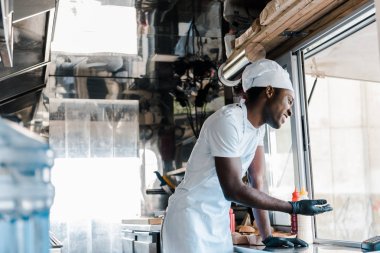 yemek kamyonunda gülümseyen neşeli Afro-Amerikan şef seçici odak 