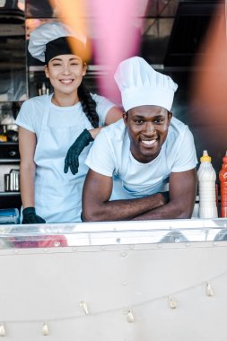 selective focus of asian girl standing near african american man in food truck  clipart