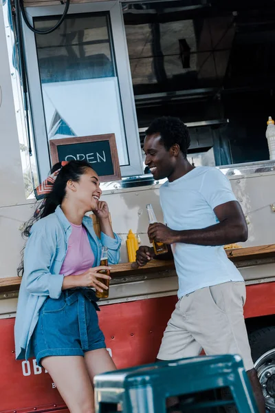 Alegre Asiático Chica Sonriendo Cerca Africano Americano Hombre Con Botella — Foto de Stock