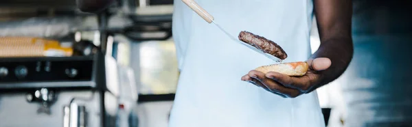Panoramiczny Strzał Afrian Amerykański Mężczyzna Trzyma Łopatki Podczas Przygotowywania Burger — Zdjęcie stockowe