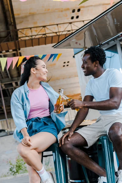Веселая Азиатская Девушка Улыбающаяся Рядом Африканским Американцем Звенящие Бутылки Пива — стоковое фото
