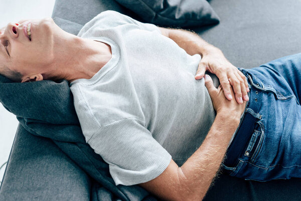 high angle view of handsome man in t-shirt with stomachache 