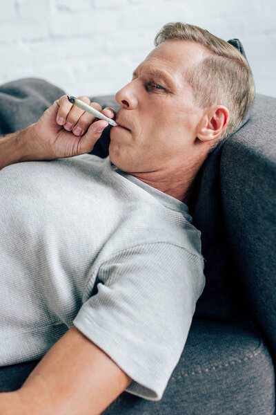 красивый мужчина курит тупой с медицинской марихуаной в квартире
 