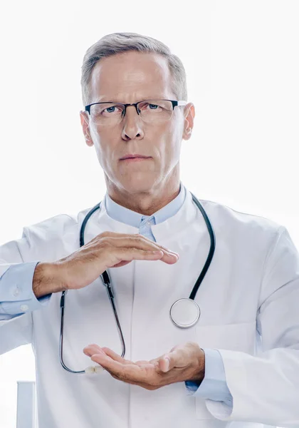 白いコートを着たハンサムな医者は 白で隔離された手を握っている — ストック写真