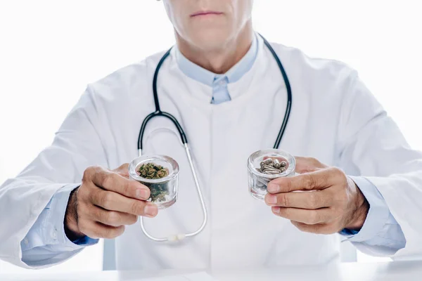 裁剪视图的医生在白色外套持有药丸和医疗大麻隔离在白色 — 图库照片
