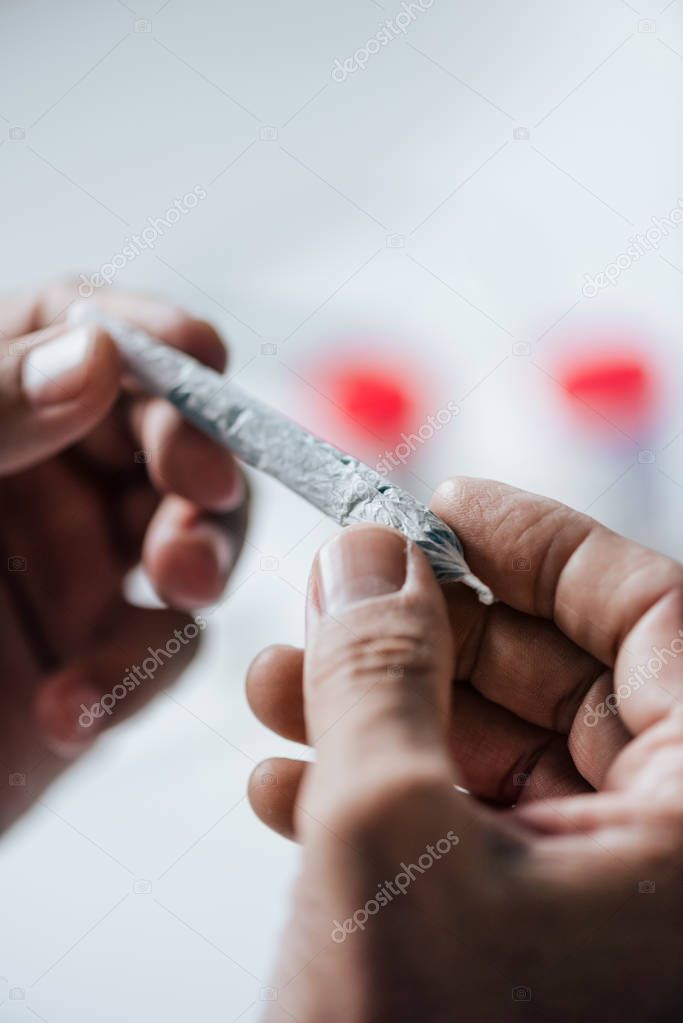 cropped view of man rolling blunt with medical cannabis