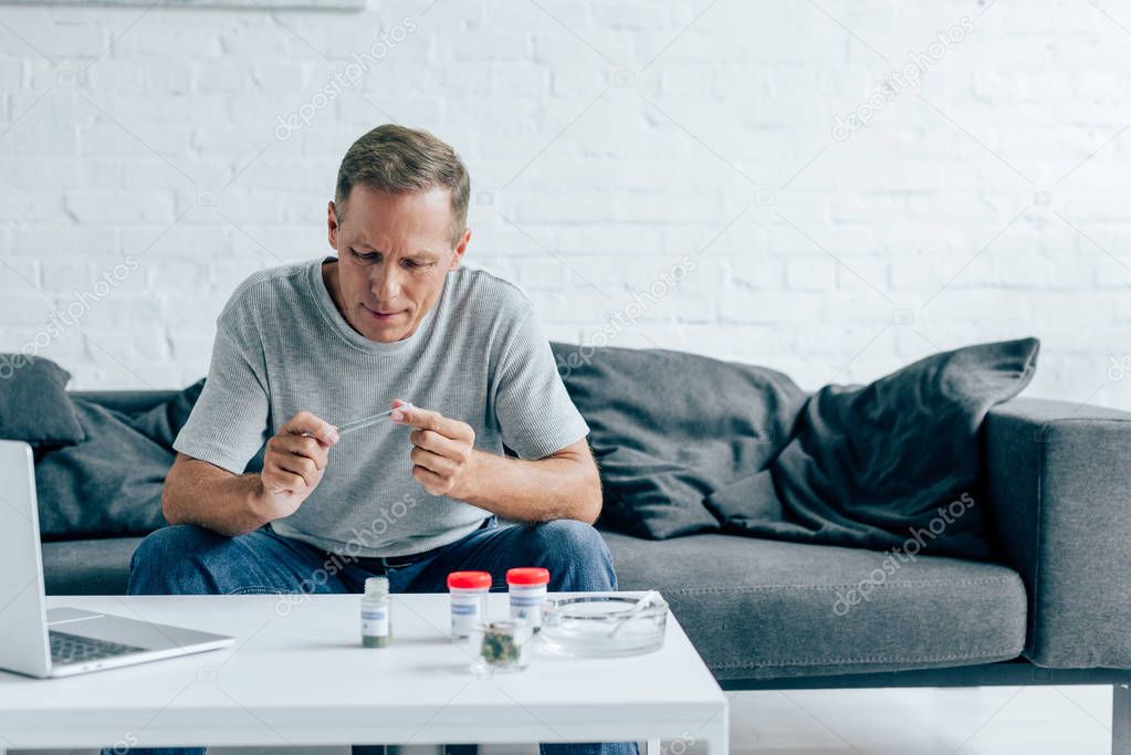 handsome man in t-shirt rolling blunt with medical cannabis