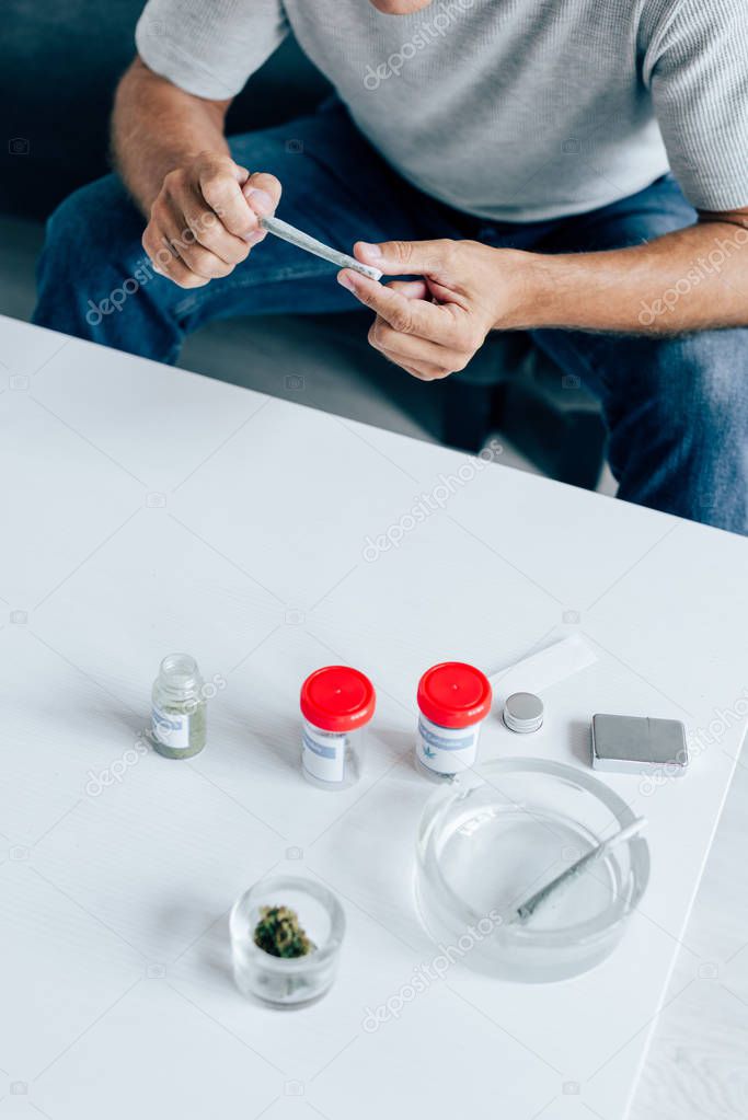 cropped view of man rolling blunt with medical cannabis