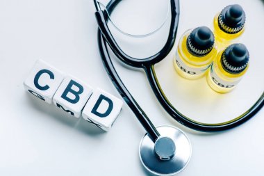 beyaz arka plan üzerinde harf cbd ve stetoskop ile küpler, kenevir yağı üst görünümü 
