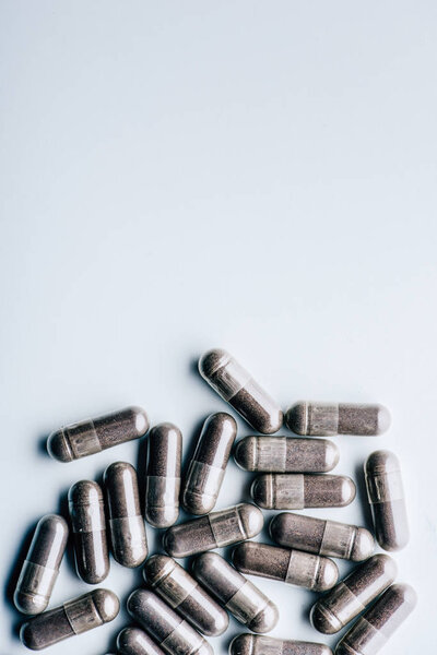 top view of black pills on white background with copy space 