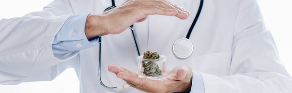 panoramic shot of doctor in white coat holding medical cannabis and pills isolated on white 