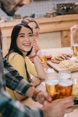 pub çok kültürlü arkadaşlar yakınında bira bardak tutan adam seçici odak