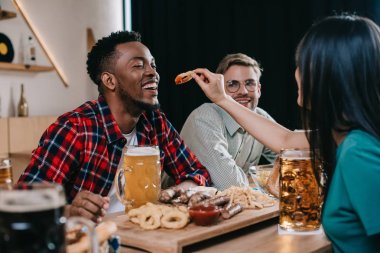 pub'da octoberfest kutlarken kızarmış soğan halkası ile afrikalı amerikalı adam besleme genç kadın geri görünümü