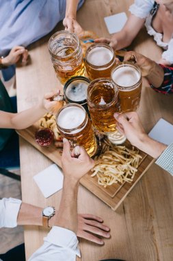 cropped view of multicultural friends clinking mugs of light and dark beer  