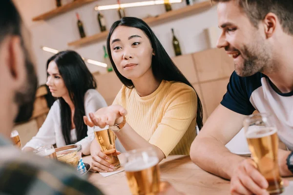 选择性的焦点年轻的亚洲女人手势 而坐在酒吧与朋友 — 图库照片