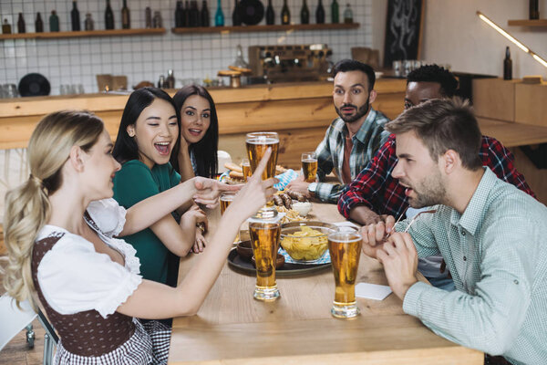 счастливые, молодые мультикультурные друзья, празднующие ocfest вместе в пабе
