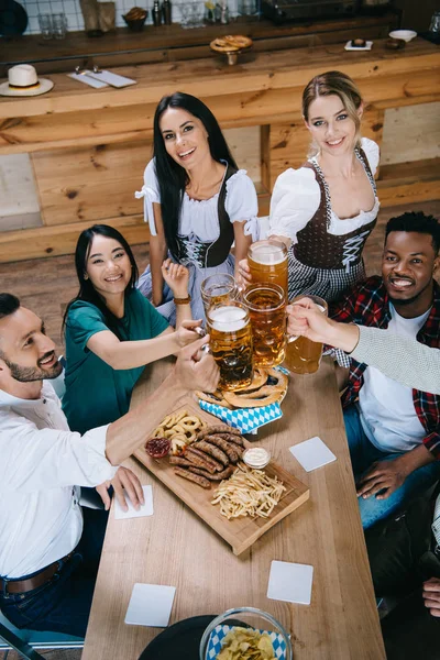 Beautiful Waitresses Traditional German Costumes Clinking Mugs Beer Multicultural Friends — Stock Photo, Image