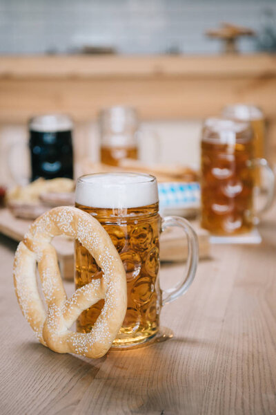 selective focus of mug with lager beer and pretzel on wooden table in pub