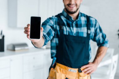 boş ekranlı akıllı telefon tutan mutlu sakallı handyman kırpılmış görünümü 