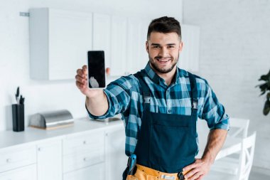 boş ekranlı akıllı telefonu tutan mutlu sakallı tamircinin seçici odağı 