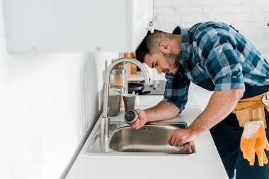 mutfakta lavabo yakınında çalışan yakışıklı sakallı tamirci seçici odak 