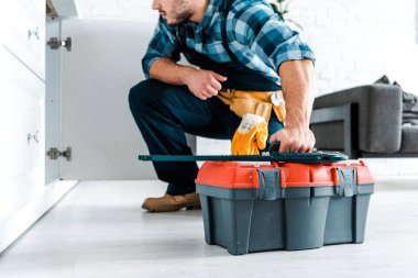 sakallı handyman oturan ve alet çantası tutan kırpılmış görünümü 